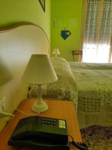 una lampada su un tavolo accanto a un letto con tastiera di Hotel Etrusco a Sesto Fiorentino