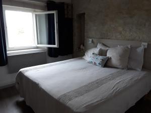 - un lit blanc avec deux oreillers et une fenêtre dans l'établissement Studio du sentier des ocres, à Roussillon