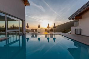 a swimming pool with the sun setting behind a house at Il Bagnolo Eco Lodge in Salò