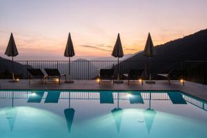 a pool with chairs and umbrellas at sunset at Il Bagnolo Eco Lodge in Salò