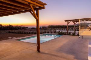 a swimming pool in a villa with a sunset in the background at Bamboo Villa Naxos in Mikri Vigla
