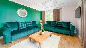 un salon vert avec deux canapés verts et une table dans l'établissement Royal Green - Apartamenty Deptak, à Karpacz