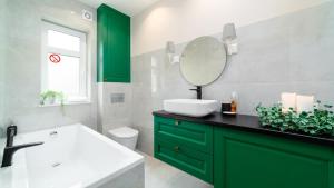 La salle de bains est pourvue de placards verts, d'un lavabo et d'un miroir. dans l'établissement Royal Green - Apartamenty Deptak, à Karpacz 25 autres photos