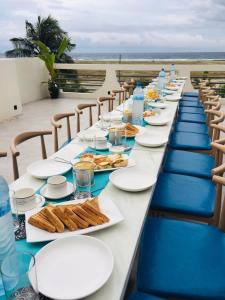 una mesa larga con platos de comida y botellas de agua en Wish Guesthouse, en Huraa