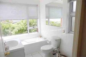 La salle de bains blanche est pourvue d'une baignoire, de toilettes et d'un lavabo. dans l'établissement Paradise@Pearly, à Pearly Beach