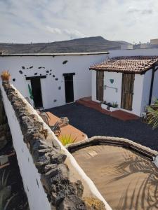 Casa blanca con pared de piedra y patio en la casita de Máguez, en Máguez