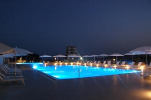 ein Pool mit Stühlen und Sonnenschirmen in der Nacht in der Unterkunft Status-M Apartments in Becici