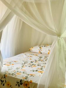 Una cama con un dosel blanco con una colcha floral. en Casa do sol, en Caraíva