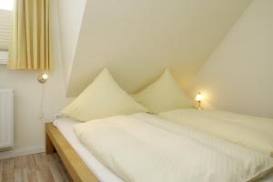 - une chambre avec 2 lits et des draps blancs dans l'établissement Ferienwohnung Mare Nostrum 9, à Westerland