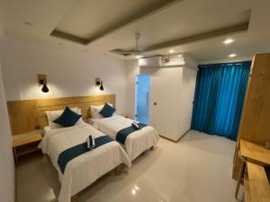 a bedroom with two beds with blue curtains at Wish Guesthouse in Huraa