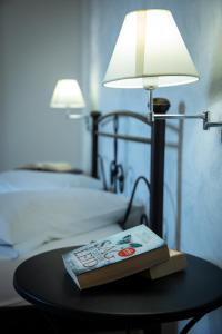 a book on a table with a lamp and a bed at Zervos Apartments Bouka in Lefkimmi