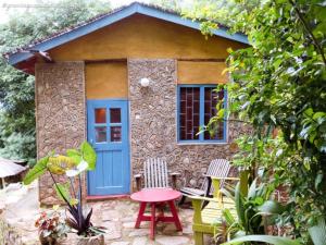 a small house with a blue door and chairs at Mayoka Village Beach Lodge in Nkhata Bay