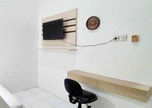 a room with a chair and a clock on a wall at Guest House Kembar Syariah Semarang RedPartner in Jatingaleh