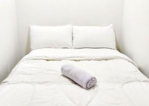 a white bed with a rolled up towel on it at Guest House Kembar Syariah Semarang RedPartner in Jatingaleh