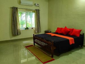 una camera da letto con un letto con cuscini rossi e una finestra di Blue Oasis a Mangalore