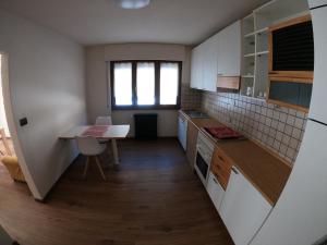 uma cozinha com armários brancos, uma mesa e uma secretária em Baggio House em Cadarese