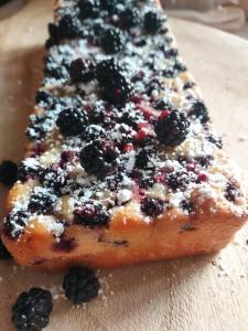 a piece of cake with blackberries on a cutting board at Maison Triton et Porcelaine in Saint-Coulomb