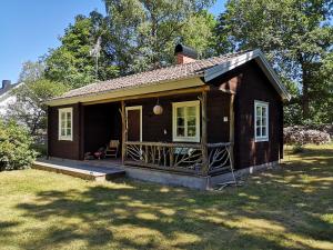 ein kleines braunes Haus mit einer Veranda und einem Hof in der Unterkunft Mysig stuga med öppen spis och uteplats in Fröseke