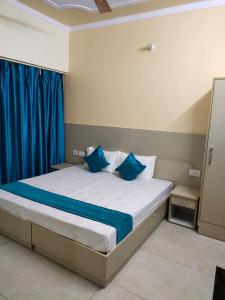 een slaapkamer met een groot bed met blauwe kussens bij Hotel Aradhana palace in Rishīkesh