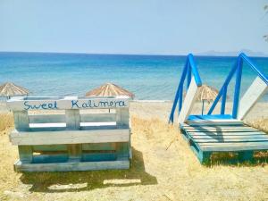 2 sillas de playa y sombrillas en una playa en Sweet Kalimera Apartments, en Kardamaina