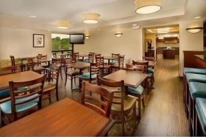 um restaurante com mesas e cadeiras de madeira e uma televisão em Hotel Lotus Kansas City Stadium em Kansas City