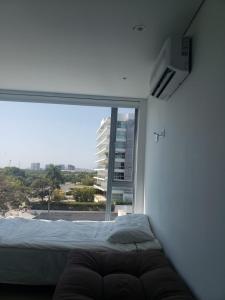 ein Schlafzimmer mit einem Bett und einem großen Fenster in der Unterkunft Playa la Boquilla, Apto dentro Condominio Hotel Sonesta in Cartagena de Indias