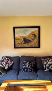 a living room with a blue couch and a painting at apartamentos turisticos san juan de la peña in Santa Cruz de la Serós