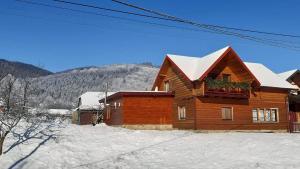ein Holzhaus mit Schnee auf dem Dach in der Unterkunft Карпатський Затишок in Huta