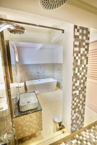 a bathroom with a bath tub and a sink at SEA SPLASH SELF CATERING And La Petite Maison in Grand Anse