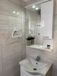a white bathroom with a sink and a mirror at Apartmani Hadžić in Živinice +75 photos