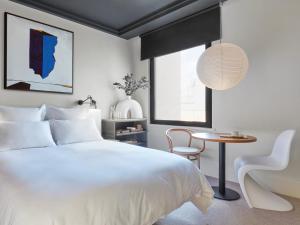 
a hotel room with a bed, chair, lamp and a window at One Hundred Shoreditch in London
