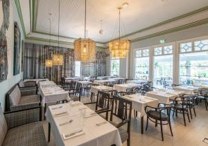 a restaurant with white tables and chairs and chandeliers at Hotelli Punkaharju in Punkaharju