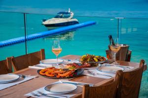 a table with two plates of food and glasses of wine at Porto Roma Seaside Studios in Vasilikos