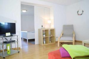 a living room with a television and a chair at DEB 035 Ferienwohnung im Westerwald in Freirachdorf