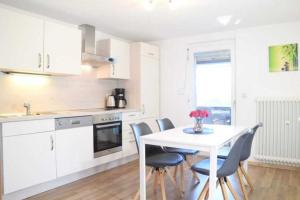 a white kitchen with a white table and chairs at DEB 035 Ferienwohnung im Westerwald in Freirachdorf