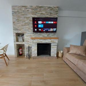 sala de estar con TV y chimenea de ladrillo en Casa Rural Benamahoma, en Benamahoma