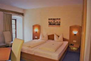 a bedroom with a large bed with a yellow chair at Hotel zum Bräu in Kinding