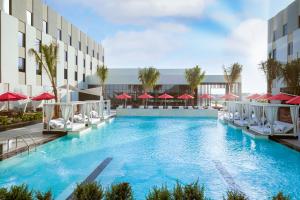 a swimming pool with chairs and umbrellas next to a building at Maani Muscat Hotel & Suites in Muscat