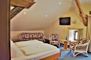 a hotel room with a bed and chairs and a tv at Hotel zum Bräu in Kinding