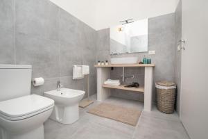 a bathroom with a toilet and a sink and a mirror at Avolio apartment in Noto