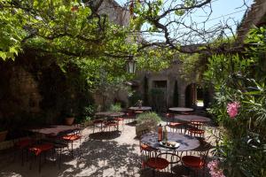 eine Terrasse mit Tischen und Stühlen im Garten in der Unterkunft Hotel De L'Atelier in Villeneuve-lès-Avignon