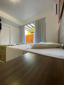 a hotel room with two beds and a window at Pousada Bernúncia in Penha