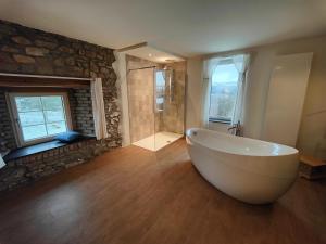 a large bathroom with a tub and a stone wall at Le Clos des Brumes in Stoumont
