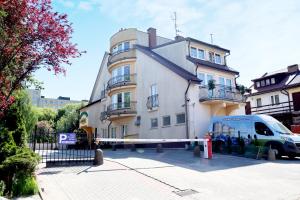 een witte bestelwagen geparkeerd voor een gebouw bij Motel Arkadia in Koszalin