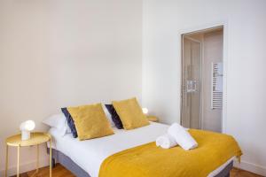 um quarto com uma grande cama branca com toques amarelos em DIFY Le Velvet - Bellecour em Lyon