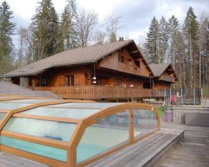 a large wooden house with a pool in front of it at Chalet Esprit in Morillon
