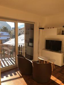 a living room with a balcony with a television and chairs at Snowboard in Valmalenco in Chiesa in Valmalenco