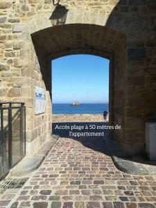 uma entrada para uma parede de pedra com vista para o oceano em Au cœur des remparts, L'ÉCRIN Appartement 2 chambres pour 2-6 pers em Saint Malo