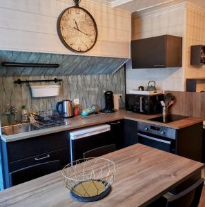 uma cozinha com uma mesa de madeira e um relógio na parede em Au cœur des remparts, L'ÉCRIN Appartement 2 chambres pour 2-6 pers em Saint Malo