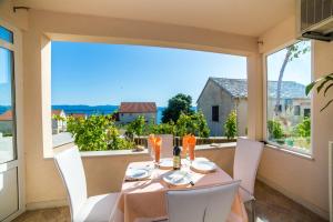 einen Esstisch mit weißen Stühlen und ein großes Fenster in der Unterkunft Apartment in Bol with sea view, terrace, air conditioning, WiFi 3739-2 in Bol